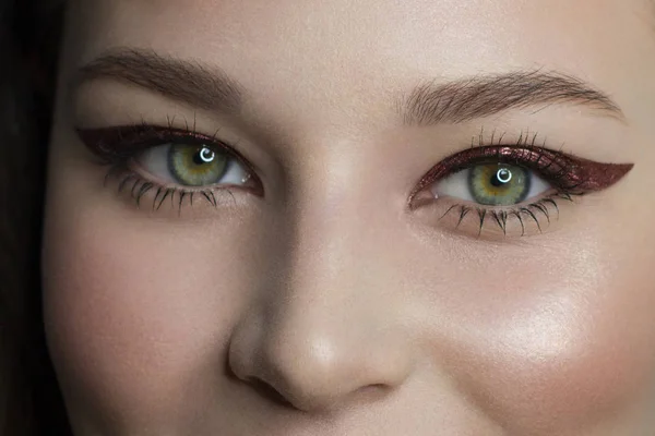 Mooie vrouw met heldere make-up oog met sexy rode voering make-up. Mode grote pijl vorm op het ooglid van de vrouw. Chique avondmake-up. Luxe extreem lange wimpers. Glanzende gezichtshuid — Stockfoto