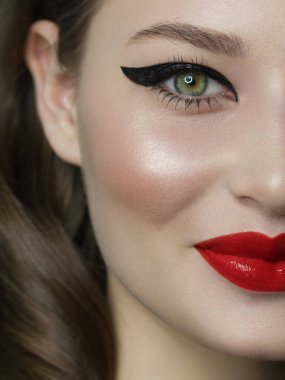 Güzel bir akşam makyajıyla yarım bir güzellik portresi, gözlerinde siyah çizgiler ve son derece uzun kirpiklerle. Dudaklarında pembe ruj izi var. Kozmetik ve kaplıca cilt bakımı