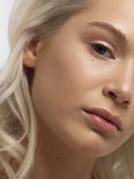 Closeup of beauty woman with clean shiny skin and natural cosmetics. Beautiful extrem eyelash and plump lips of a well-groomed girl demonstrate spa procedures, injections in a beauty parlor