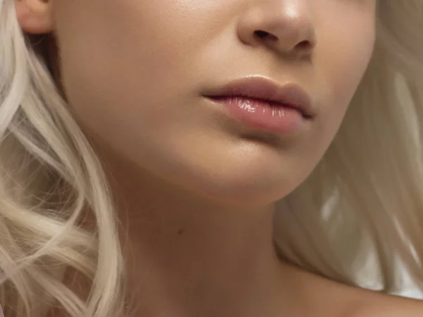 Крупный план губ женщины с модой натуральный бежевый макияж помады. Макро сексуальный бледный макияж для губ. Нежная чистая кожа и волнистые светлые волосы. косметология, спа, увеличение губ — стоковое фото