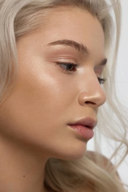 Düz saçlı bir kadının yakın plan portresi. Sevimli genç sarışın kız. Doğal ruj, şeffaf temiz ten. Spa salonunda ya da kozmetolojide cilt bakımı doğal kozmetik ürünleri.