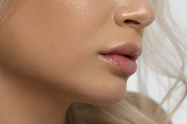 Close-up van de lippen van de vrouw met mode natuurlijke beige lippenstift make-up. Macro sexy bleke lipgloss make-up. Zachte zuivere huid en golvend blond haar. Cosmetologie, Spa, toename van de lippen — Stockfoto