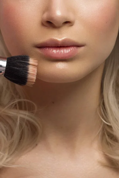 Close-up of woman\'s lips with fashion natural beige lipstick makeup. Macro sexy pale lipgloss make-up . Gentle pure skin and wavy blonde hair. Cosmetology, Spa, increase in lips. Face powder