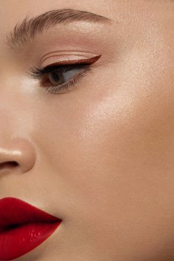 Yaratıcı moda gecesi makyajlı, yarı kadın yüzünün yakın plan güzelliği. Gözlerde siyah oklar ve son derece uzun kirpiklerde, dolgun dudaklarda kırmızı dudak rengi. Kaplıcadan sonra iyi bakımlı cilt