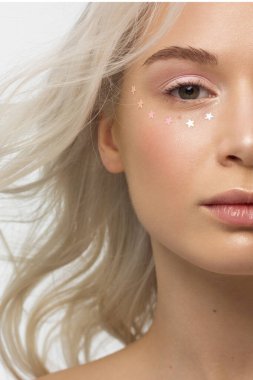 Açık tenli ve kıvırcık sarı saçlı bir kadının yarım portresi. Gözlerde yapay elmaslar, çıplak makyaj ve doğal ruj. yumuşak bakım, dolgun dudaklar, uzun kirpikler ve kalın kaşlar.