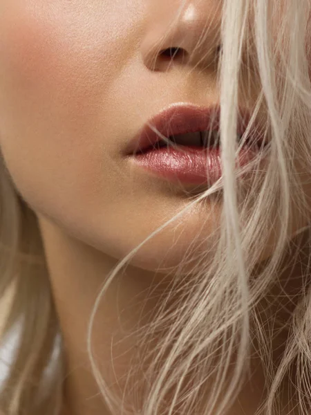 Sexual full lips. Natural gloss of lips and woman\'s skin. The mouth is closed. Increase in lips, cosmetology. Pink lips and long neck. Gentle pure skin and wavy blonde hair.