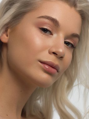 Düz saçlı bir kadının yakın plan portresi. Sevimli genç sarışın kız. Doğal ruj, şeffaf temiz ten. Spa salonunda ya da kozmetolojide cilt bakımı doğal kozmetik ürünleri.