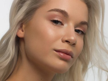 Düz saçlı bir kadının yakın plan portresi. Sevimli genç sarışın kız. Doğal ruj, şeffaf temiz ten. Spa salonunda ya da kozmetolojide cilt bakımı doğal kozmetik ürünleri.