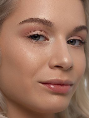 Düz saçlı bir kadının yakın plan portresi. Sevimli genç sarışın kız. Doğal ruj, şeffaf temiz ten. Spa salonunda ya da kozmetolojide cilt bakımı doğal kozmetik ürünleri.