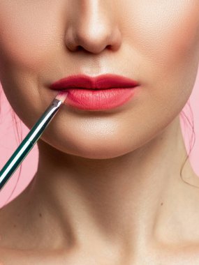Kadın Pembe dudakları boyalı. Güzellik dudak makyaj. Mükemmel cilt, dolgun dudaklar. Retro makyaj. Profesyonel makyaj sanatçısı seksi dudak makyaj uygulamak. Moda makyaj