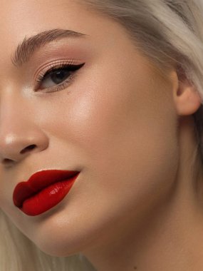 Yaratıcı moda gecesi makyajlı, yarı kadın yüzünün yakın plan güzelliği. Gözlerde siyah oklar ve son derece uzun kirpiklerde, dolgun dudaklarda kırmızı dudak rengi. Kaplıcadan sonra iyi bakımlı cilt