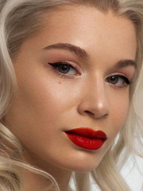Düz saçlı bir kadının yakın plan portresi. Sevimli genç sarışın kız. Kırmızı ruj, şeffaf temiz ten. Spa salonunda ya da kozmetolojide cilt bakımı doğal kozmetik ürünleri.