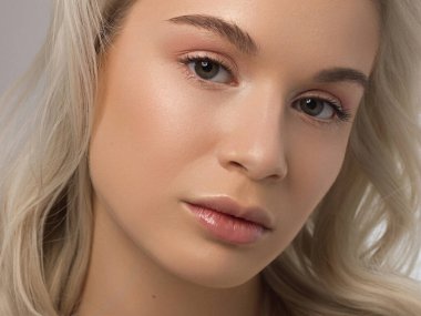 Düz saçlı bir kadının yakın plan portresi. Sevimli genç sarışın kız. Doğal ruj, şeffaf temiz ten. Spa salonunda ya da kozmetolojide cilt bakımı doğal kozmetik ürünleri.