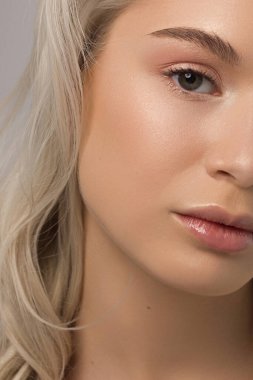 Temiz ciltli ve doğal kozmetik ürünleri olan yarı güzel bir kadın. Güzel, ekstrem kirpik ve bakımlı bir kızın dolgun dudakları güzellik salonunda spa prosedürleri, enjeksiyonlar gösteriyor. Sarı saç.
