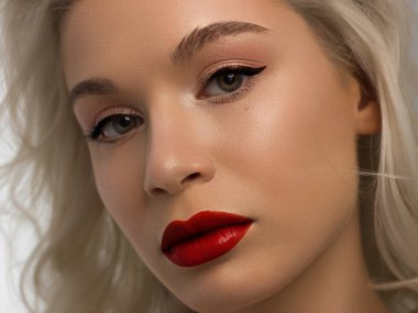 Düz saçlı bir kadının yakın plan portresi. Sevimli genç sarışın kız. Kırmızı ruj, şeffaf temiz ten. Spa salonunda ya da kozmetolojide cilt bakımı doğal kozmetik ürünleri.