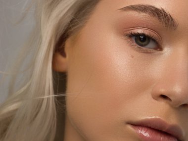 Temiz ciltli ve doğal kozmetik ürünleri olan yarı güzel bir kadın. Güzel, ekstrem kirpik ve bakımlı bir kızın dolgun dudakları güzellik salonunda spa prosedürleri, enjeksiyonlar gösteriyor. Sarı saç.