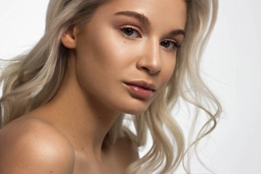 Düz saçlı bir kadının yakın plan portresi. Sevimli genç sarışın kız. Doğal ruj, şeffaf temiz ten. Spa salonunda ya da kozmetolojide cilt bakımı doğal kozmetik ürünleri.