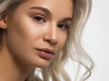 Düz saçlı bir kadının yakın plan portresi. Sevimli genç sarışın kız. Doğal ruj, şeffaf temiz ten. Spa salonunda ya da kozmetolojide cilt bakımı doğal kozmetik ürünleri.