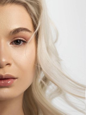 Temiz ciltli ve doğal kozmetik ürünleri olan yarı güzel bir kadın. Güzel, ekstrem kirpik ve bakımlı bir kızın dolgun dudakları güzellik salonunda spa prosedürleri, enjeksiyonlar gösteriyor. Sarı saç.