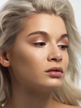 Düz saçlı bir kadının yakın plan portresi. Sevimli genç sarışın kız. Doğal ruj, şeffaf temiz ten. Spa salonunda ya da kozmetolojide cilt bakımı doğal kozmetik ürünleri.