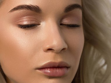 Düz saçlı bir kadının yakın plan portresi. Sevimli genç sarışın kız. Doğal ruj, şeffaf temiz ten. Spa salonunda ya da kozmetolojide cilt bakımı doğal kozmetik ürünleri.