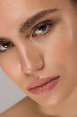 Siyah dumanlı göz makyajı ve doğal dolgun dudakları olan güzel bir kadının temiz yüzünün yakın plan portresi. Temiz ciltli, temiz yüzlü, uzun kıvırcık saçlı seksi bir manken. göz kamaştırıcı görüntü