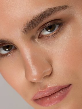 Siyah dumanlı göz makyajı ve doğal dolgun dudakları olan güzel bir kadının temiz yüzünün yakın plan portresi. Temiz ciltli, temiz yüzlü, uzun kıvırcık saçlı seksi bir manken. göz kamaştırıcı görüntü