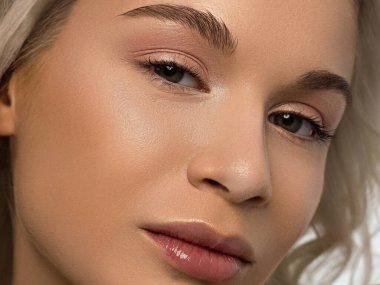 Düz saçlı bir kadının yakın plan portresi. Sevimli genç sarışın kız. Doğal ruj, şeffaf temiz ten. Spa salonunda ya da kozmetolojide cilt bakımı doğal kozmetik ürünleri.