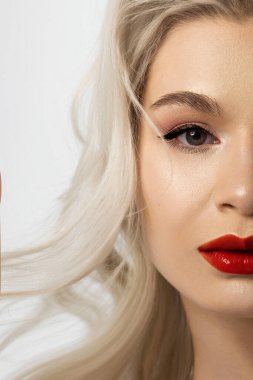 Yaratıcı moda gecesi makyajlı, yarı kadın yüzünün yakın plan güzelliği. Gözlerde siyah oklar ve son derece uzun kirpiklerde, dolgun dudaklarda kırmızı dudak rengi. Kaplıcadan sonra iyi bakımlı cilt