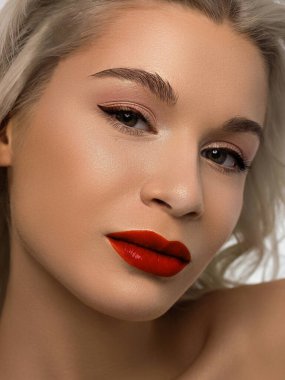 Düz saçlı bir kadının yakın plan portresi. Sevimli genç sarışın kız. Kırmızı ruj, şeffaf temiz ten. Spa salonunda ya da kozmetolojide cilt bakımı doğal kozmetik ürünleri.