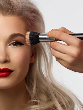 Yaratıcı moda gecesi makyajlı, yarı kadın yüzünün yakın plan güzelliği. Gözlerde siyah oklar ve son derece uzun kirpiklerde, dolgun dudaklarda kırmızı dudak rengi. Kaplıcadan sonra iyi bakımlı cilt