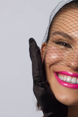 Düğüm ve peçeli, siyah göz kalemi ve pembe rujlu, şık yarı güzel bir kadın. Temiz ve parlak cilt, doğal dudak parlatıcısı, kalın kaşlar ve uzun kirpikleri. Kozmetik ve makyaj.