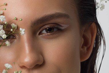 Güzel derisi, çıplak makyajı, göz kalemi, uzun kirpikleri, kabarık doğal dudakları ve beyaz çiçekleri olan bir yüz portresi. Moda fotoğrafçılığı. Kozmetik ve kaplıca. Baharın tazeliği