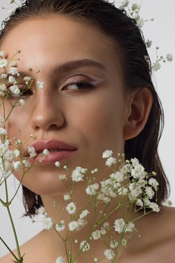 Güzel derisi, çıplak makyajı, göz kalemi, uzun kirpikleri, kabarık doğal dudakları ve beyaz çiçekleri olan bir yüz portresi. Moda fotoğrafçılığı. Kozmetik ve kaplıca. Baharın tazeliği