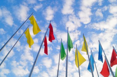 Renkli bayrak beyaz bulutlar, çok güzel ve mavi gökyüzü altında.