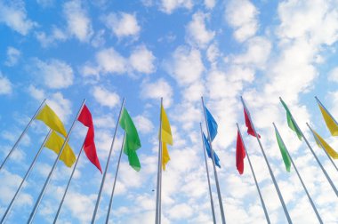 Renkli bayrak beyaz bulutlar, çok güzel ve mavi gökyüzü altında.