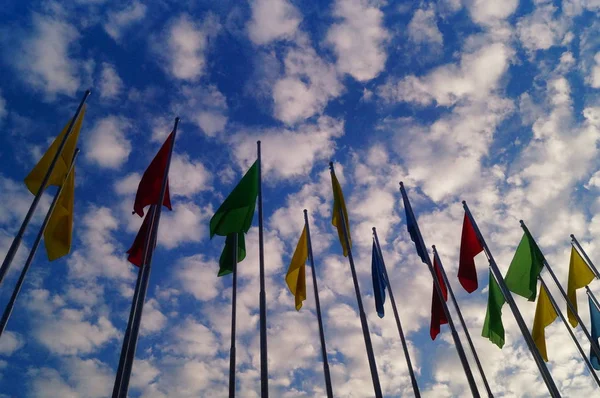 Πολύχρωμο σημαία κάτω από την μπλε ουρανό και άσπρα σύννεφα, πολύ όμορφη. — Φωτογραφία Αρχείου