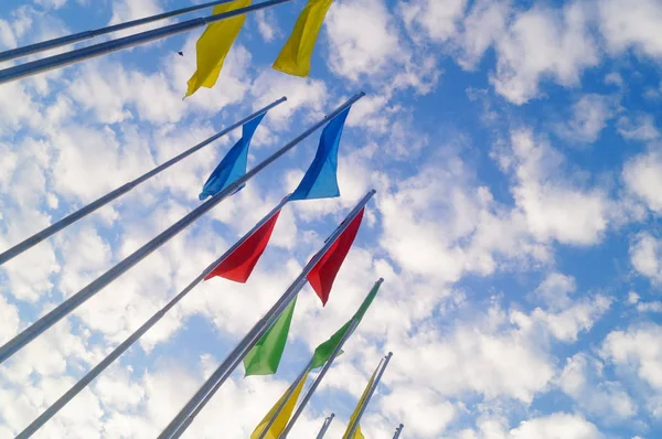 Bandera de colores bajo el cielo azul y nubes blancas, muy hermosa . — Foto de Stock