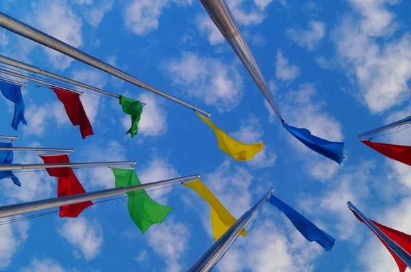 Bandera de colores bajo el cielo azul y nubes blancas, muy hermosa . — Foto de Stock