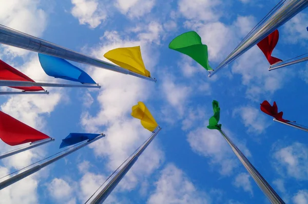 Bandera de colores bajo el cielo azul y nubes blancas, muy hermosa . — Foto de Stock