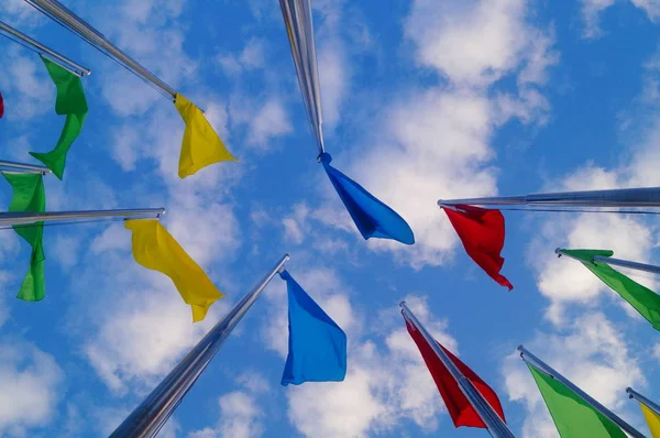 Bandera de colores bajo el cielo azul y nubes blancas, muy hermosa . — Foto de Stock