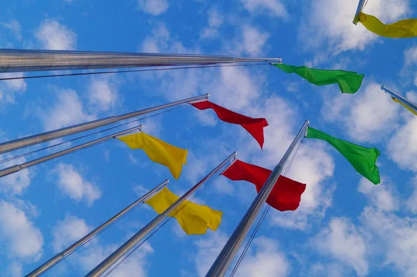 Bandera de colores bajo el cielo azul y nubes blancas, muy hermosa . — Foto de Stock