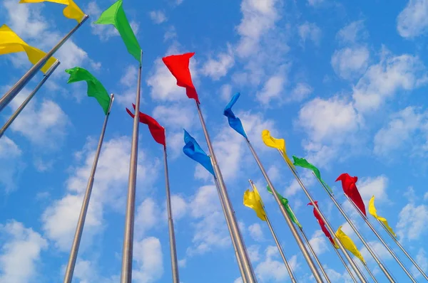 Bandera de colores bajo el cielo azul y nubes blancas, muy hermosa . — Foto de Stock