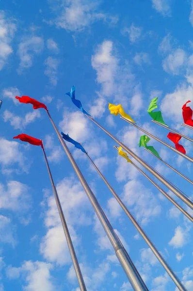 Bandera de colores bajo el cielo azul y nubes blancas, muy hermosa . — Foto de Stock