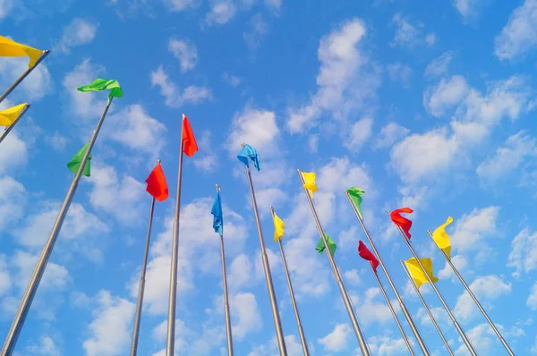 Bandera de colores bajo el cielo azul y nubes blancas, muy hermosa . — Foto de Stock