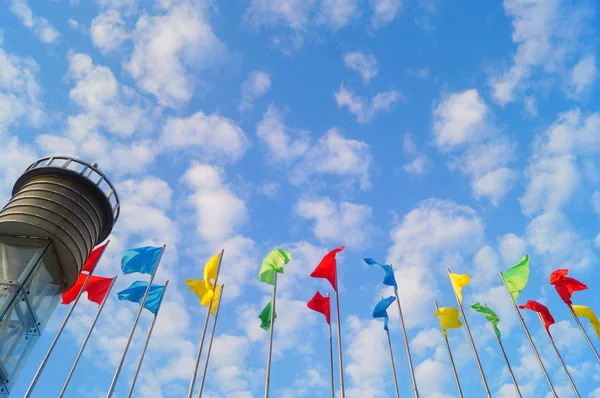 Bandera de colores bajo el cielo azul y nubes blancas, muy hermosa . — Foto de Stock