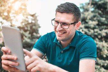 Genç adam tablet bankta bir yaz gününde kullanma.