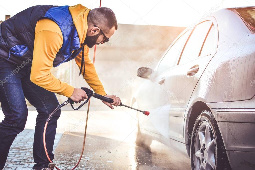 Man washing his car in a self-service car wash station