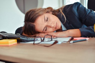 Masanın üzerinde uyuyan overworked ve yorgun genç kadın
