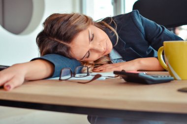Masanın üzerinde uyuyan overworked ve yorgun genç kadın